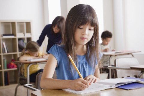 Schoolgirl focused on writing. 
Photo : Rob Lewine