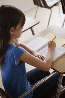 Schoolgirl focused on writing. 
Photo : Rob Lewine