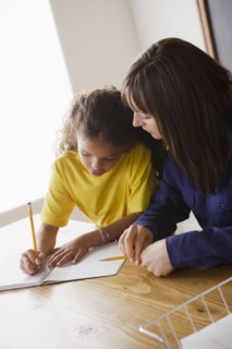 Schoolgirl writing with teacher in classroom. 
Photo: Rob Lewine