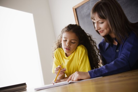 Schoolgirl writing with teacher in classroom. 
Photo: Rob Lewine