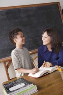 Schoolboy reading with teacher in classroom. 
Photo: Rob Lewine