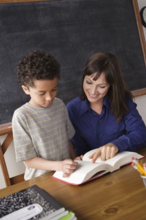 Schoolboy reading with teacher in classroom. 
Photo: Rob Lewine