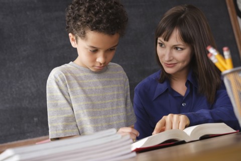 Schoolboy reading with teacher in classroom. 
Photo: Rob Lewine