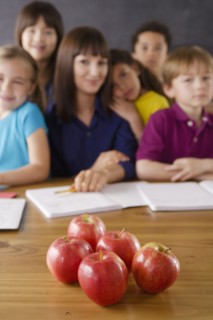 Teacher with group of pupils and apples on desk. 
Photo : Rob Lewine