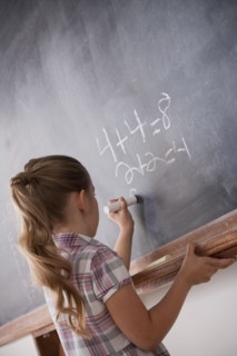 Schoolboy writing on blackboard. 
Photo : Rob Lewine