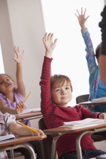 Pupils in classroom raising hands. 
Photo : Rob Lewine