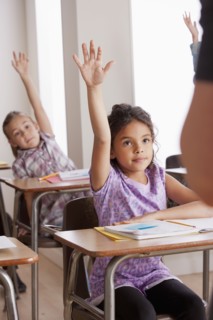Pupils in classroom raising hands. 
Photo : Rob Lewine