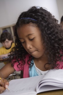 Writing girl (10-11) with boy (10-11) in background. 
Photo : Rob Lewine