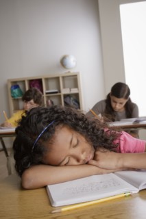 Girl (10-11) napping on desk with girl (12-13) and boy (10-11) in background. 
Photo : Rob Lewine