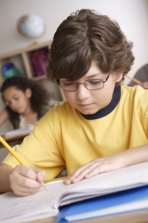 Writing boy (10-11) with girl (10-11) in background. 
Photo : Rob Lewine