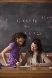 Schoolgirl (10-11) and teacher with blackboard in background. 
Photo : Rob Lewine