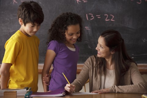 Teacher explaining exercise to schoolgirl (10-11) and schoolboy (12-13). 
Photo: Rob Lewine