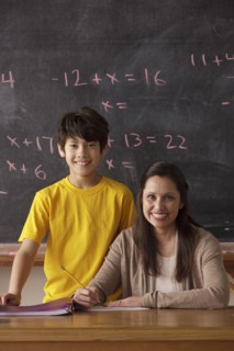 Portrait of schoolboy (12-13) and teacher with blackboard in background. 
Photo : Rob Lewine