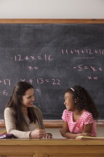 Schoolgirl (10-11) and teacher face to face with blackboard in background. 
Photo: Rob Lewine