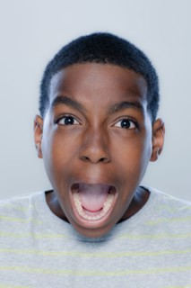 Portrait of teenage boy (14-15) screaming, studio shot. 
Photo : Rob Lewine
