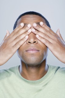 Young man with hands covering eyes, studio shot. 
Photo : Rob Lewine
