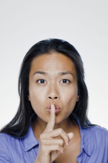 Portrait of young woman with finger on lips, studio shot. 
Photo: Rob Lewine