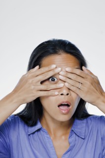 Portrait of young woman with hands covering eyes, studio shot. 
Photo : Rob Lewine