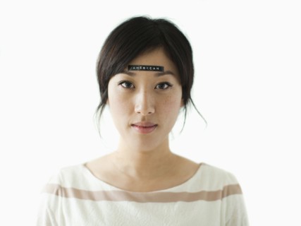 Portrait of young woman with word 'American' on forehead, studio shot. 
Photo: Jessica Peterson