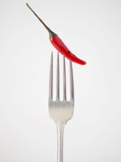 Chilli pepper on fork, studio shot. 
Photo : Jessica Peterson