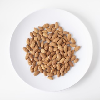 Almonds on plate, studio shot. 
Photo : Jessica Peterson