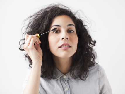 Beautiful young woman applying mascara. 
Photo : Jessica Peterson