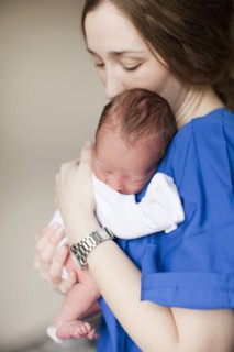Portrait of young female nurse holding baby boy (2-5 months). 
Photo : Jessica Peterson