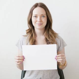 Portrait of cheerful young woman holding blank card. 
Photo : Jessica Peterson