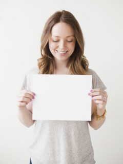 Portrait of cheerful young woman holding blank card. 
Photo : Jessica Peterson