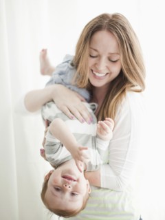 Portrait of young woman embracing baby boy (6-11 months) upside-down. 
Photo : Jessica Peterson