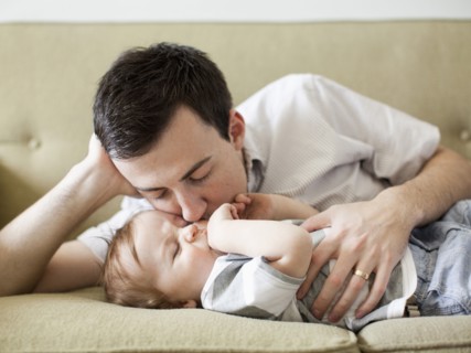 Father and baby boy (6-11 months) lying on sofa. 
Photo : Jessica Peterson