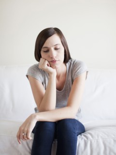 Bored young woman sitting on bed. 
Photo : Jessica Peterson