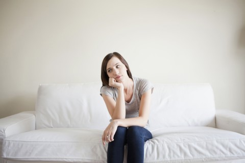 Bored young woman sitting on bed. 
Photo : Jessica Peterson