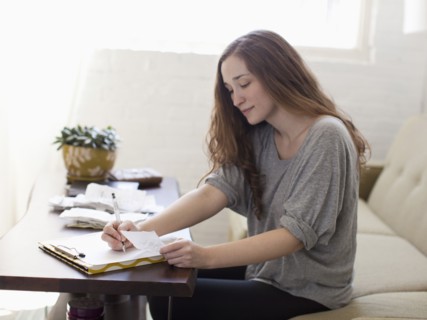 Young woman going though domestic paperwork. 
Photo : Jessica Peterson