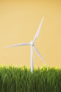 Model wind turbines in grass on yellow background.