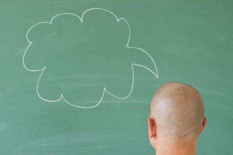 Man in front of blackboard with drawing depicting speech bubble.