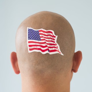 Back view of man with American flag tattoo on head.