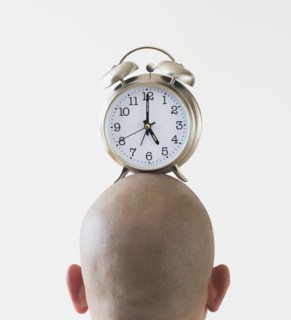 Back view of man with alarm clock on shaved head.