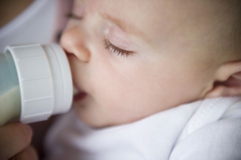 Mother feeding baby boy (2-5 months) using feeding bottle. Photo : Jamie Grill