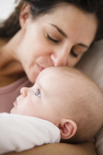 Mother and baby boy (2-5 months) lying together on bed. Photo : Jamie Grill