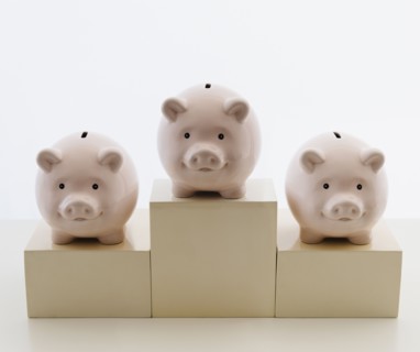 Three piggy banks in arranged on sports podium. Photo : Jamie Grill