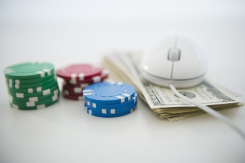 Roulette tokens, dollar bills and computer mouse. Photo : Jamie Grill