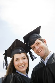 Young man and woman wearing graduation gowns. Photo : Jamie Grill