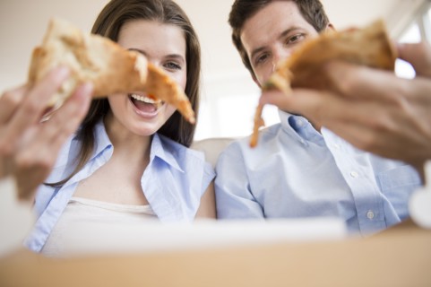 Happy young couple eating pizza. Photo : Jamie Grill