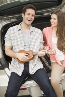 Happy young couple sitting in car boot with mandolin. Photo: Jamie Grill