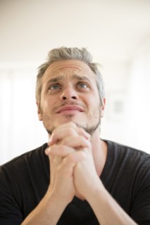 Mid adult man in praying gesture. Photo: Jamie Grill