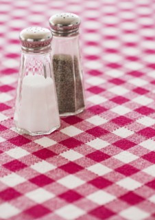 Salt and pepper shakers on checked tablecloth. Photo : Daniel Grill
