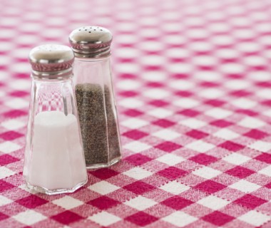 Salt and pepper shakers on checked tablecloth. Photo : Daniel Grill