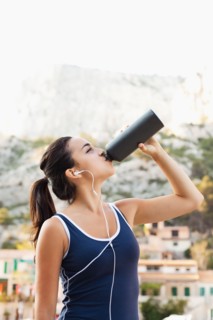 France, Marseille, Young woman in tracksuit drinking water. Photo : Mike Kemp