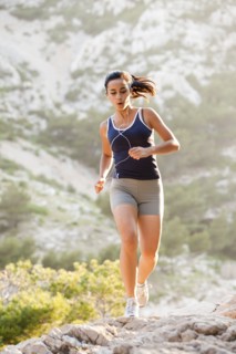 France, Marseille, Young woman jogging on rocky terrain. Photo : Mike Kemp